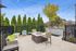 Charming outdoor patio with cozy seating, a central fire pit, and elegant string lights against a backdrop of lush greenery.