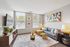 Bright and modern living room with large windows, stylish gray sofa, colorful geometric artwork, and chic decor accents.