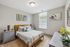 Bright and inviting bedroom with a stylish wooden bed, cozy pillows, and modern decor, perfect for relaxation and comfort.