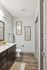 Contemporary bathroom with elegant wood flooring, sleek dark cabinetry, and stylish wall art for a modern touch.