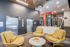 Modern apartment lobby featuring cozy yellow armchairs, sleek elevators, and vibrant decor.