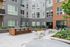 Modern apartment courtyard featuring stylish outdoor seating, a communal barbecue area, and lush greenery for a vibrant living experience.
