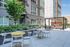 Modern apartment courtyard with vibrant seating, lush greenery, and a stylish pergola, perfect for outdoor relaxation.