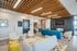 Modern communal lounge featuring sleek wooden ceiling design, vibrant seating, and contemporary art decor.