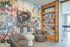 Contemporary reading nook with vibrant abstract wall art, stylish circular chairs, and a wooden bookshelf filled with colorful books.