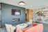 Modern living room featuring a chic coral sofa, stylish chairs, and a vibrant accent wall with contemporary art.