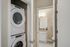 Modern apartment with a stacked washer-dryer unit near a chic bathroom with granite countertops and elegant lighting.