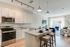 Bright and modern open-concept kitchen and living room with granite countertops, stainless steel appliances, and large windows filling the space with natural light.