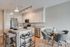 Modern kitchen with sleek stainless steel appliances, granite countertops, and cozy dining area featuring stylish gray chairs.