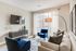 Modern living room with elegant blue armchairs, cozy beige sofa, and stylish decor under soft natural lighting from large windows.