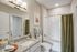 Elegant bathroom with a modern granite countertop vanity, chic lighting, and a pristine bathtub with olive green curtains.