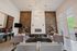 Luxurious living room with chic sofas, elegant lighting, and a modern fireplace framed by a striking stone accent wall.