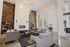 Luxurious and modern living room with high ceilings, elegant chandeliers, and a sophisticated stone fireplace. Features plush seating and abundant natural light for an inviting atmosphere.