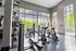 Bright and spacious apartment gym with modern exercise equipment and large windows offering scenic views.