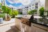 Modern apartment complex with lush greenery, featuring a stylish outdoor grill and inviting pool area under a bright, blue sky.
