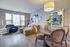 Inviting living space with modern d&eacute;cor, featuring a plush sectional sofa, stylish armchair, and elegant dining area with lush greenery.