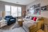 Chic living room with elegant decor, featuring a plush sectional sofa and modern armchair, bathed in natural light from large windows.