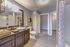 Elegant bathroom with a modern vanity, spacious mirror, and sleek flooring, featuring soft lighting and stylish decor.