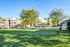 Beautiful apartment complex with lush green open space, mature trees, and modern architecture, perfect for outdoor relaxation.
