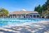 Inviting outdoor pool area with lounge chairs and a charming poolside house, surrounded by lush greenery and under a clear blue sky.