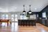 Luxurious open-plan entertainment area featuring a modern kitchen with elegant pendant lighting, sleek dark cabinets, and a stylish bar area overlooking a chic pool table.