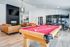 Sleek and modern entertainment room with vibrant red pool table, cozy leather sofas, and a stylish fireplace, perfect for hosting and relaxation.