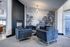 Chic lounge space with elegant blue armchairs, modern fireplace, and artistic nature wall mural, creating a serene ambiance.