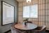 Cozy dining area with stylish round table and plush chairs, accented by a motivational quote on the wall and natural light through a large window.