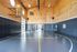 Spacious indoor basketball court with modern flooring and warm wooden accents, featuring ample natural light and seating area.