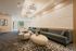 Elegant living area with modern seating, stylish textured wall art, and abundant natural light, perfect for relaxation.