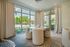 Bright and modern dining area with large windows, featuring elegant cream furniture and a contemporary round table.