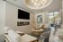 Bright and inviting living room with elegant decor, large windows, modern lighting, and a sleek wall-mounted fireplace beneath a widescreen TV.