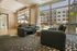 Modern lounge area with plush seating and large windows overlooking a sunlit courtyard, perfect for relaxation.
