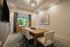 Elegant dining room featuring a large wooden table, cushioned chairs, and modern decor with a garden view.