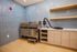 Contemporary laundry room featuring sleek stainless steel utility sink, stylish blue tile walls, and modern wooden shelving.