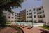 Modern apartment complex with a luxurious pool area, surrounded by lounge chairs and lush greenery, offering a relaxing outdoor retreat.