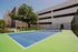 Inviting outdoor tennis court surrounded by lush greenery and modern architecture, perfect for leisurely matches in a vibrant community setting.