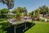 Spacious outdoor recreation area featuring a sleek ping pong table surrounded by lush greenery and palm trees, perfect for leisure and entertainment.