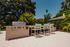 Chic outdoor patio with a modern grill and stylish seating, surrounded by lush greenery.