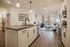 Modern open-concept kitchen and living room with elegant fixtures, stylish artwork, and large window allowing natural light.