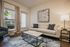 Chic living room featuring a stylish white couch, modern marble coffee table, and abstract wall art, with large window allowing natural light.