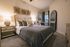 Elegant bedroom with modern decor, featuring a cozy bed with plush pillows, unique wall art, and ambient lighting, creating a serene and inviting atmosphere.