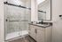 Elegant bathroom featuring a sleek marble-tiled shower, contemporary vanity with ample storage, and modern fixtures.