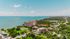 Breathtaking aerial view of coastal apartments surrounded by lush greenery and stunning oceanfront, ideal for a serene living experience.