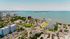 Scenic aerial view showcasing stunning waterfront apartments with lush greenery, palm-lined streets, and expansive ocean vistas.