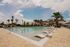 Luxurious apartment pool area with inviting loungers, surrounded by palm trees and a bright, sunny sky.