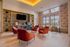Contemporary lounge area with vibrant decor, featuring plush orange chairs, geometric tiled flooring, large windows, and a chic entertainment setup.