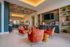 Chic communal lounge with luxurious orange chairs, bespoke cabinetry, and a modern open kitchen design, perfect for entertaining.