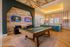 Modern recreation room with a stylish pool table, arcade games, and chic bar seating under a warm, inviting ceiling light design.