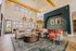Elegant living room with high ceilings, natural light, and stylish decor featuring a large sofa, modern rug, and colorful accent chairs.